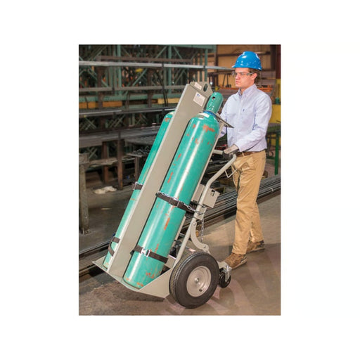 A Man Using the Justrite Double Cylinder Hand Truck with Firewall & Hoist Ring, 16" Pneumatic Wheels, Rear Casters, Tool Box - 35052